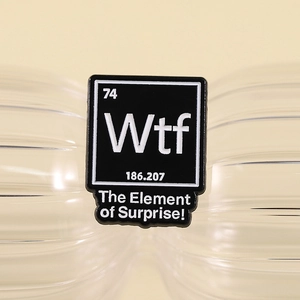 Funny WTF periodic table enamel pin with 'The Element of Surprise' on beige background