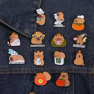 Détail de 12 pin's en émail capybara assortis présentés sur un tissu en denim bleu
