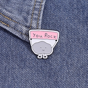 Detailansicht der You Rock Emaille-Anstecknadel auf Denim mit grauem Stein und Banner