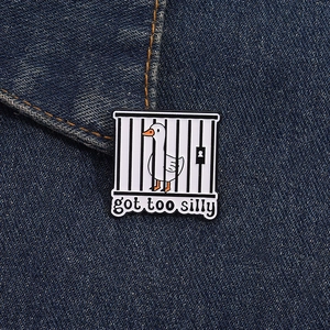 Macro detail of silly goose metal enamel pin with got too silly text on denim fabric