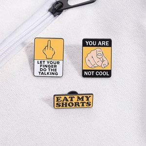 Detailed close-up of three metal enamel pins with yellow warning signs on canvas bag