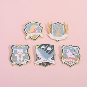 Cute shield-shaped enamel animal pins featuring unicorn and bear on pink background