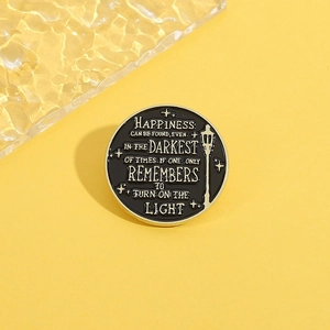 Round enamel pin with lamp design and inspirational quote on a yellow background
