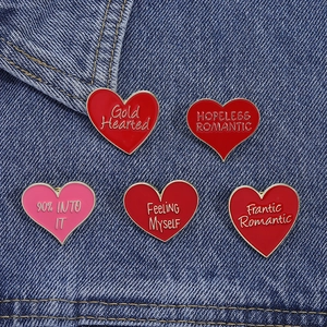 Detail of red and pink enamel heart pins with gold edges on a blue denim background