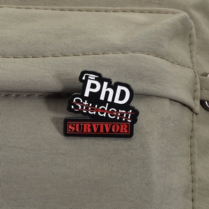 Vue détaillée du pin's émaillé PhD Survivor sur une sangle de sac à dos