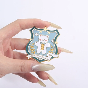Detailed close-up of shield-shaped enamel pin with white bear and strength courage text