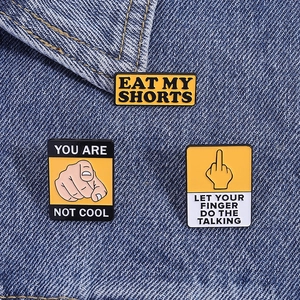 Close-up of three yellow sarcastic enamel pins pinned on dark blue denim fabric