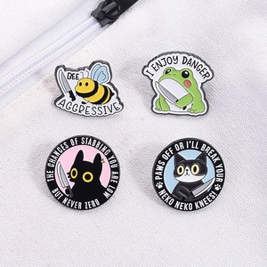 Detail of funny animal enamel pins with cat and bee characters on white canvas fabric