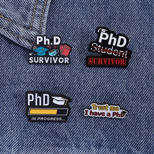 Détail des épingles en émail PhD avec chapeau de diplômé et livres sur fond de jean bleu