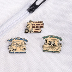 Detailed close-up of three enamel animal pins on a white canvas bag showing bear and raccoon