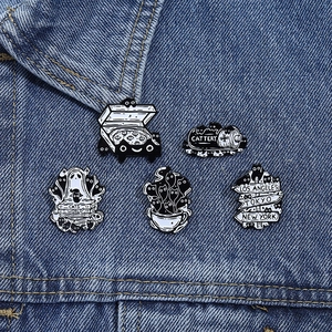 Detailed set of 5 black and white enamel cat pins displayed on blue denim fabric