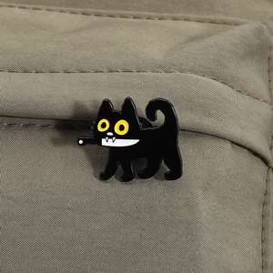 Macro shot of a cute black cat enamel pin on a khaki canvas bag showing glossy finish
