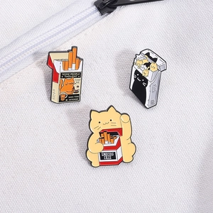 Detailed macro view of three enamel cat cigarette box pins on white canvas fabric