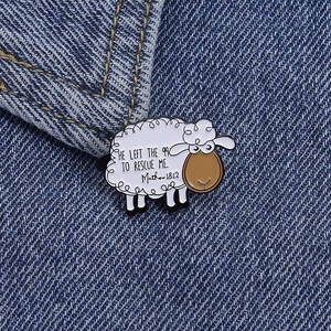 Detail of white sheep enamel pin with religious quote on blue denim jacket texture