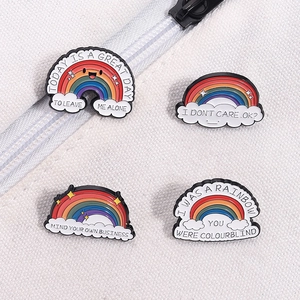 Rainbow metal enamel pin set with motivational quotes on a white textured background