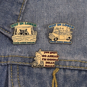 Detailed view of three cute enamel pins with animal designs on denim fabric background