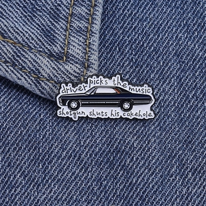 Detail of metal enamel pin with vintage car design and quote on blue denim fabric