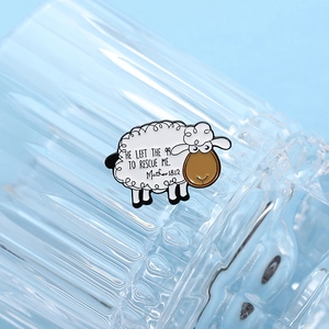 Detailed macro shot of a white sheep enamel pin with engraved religious quote text