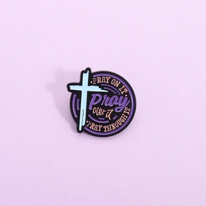 Creative circular enamel pin with blue cross and purple pray on it inspirational text