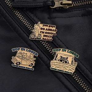 Detailed view of three metal enamel pins with humorous animal designs on a black jacket