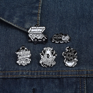 Detailed set of five black and white enamel cat pins displayed on blue denim fabric