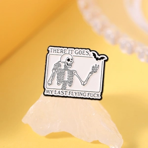 Macro shot of skull enamel pin with satirical text on a white crystal display base