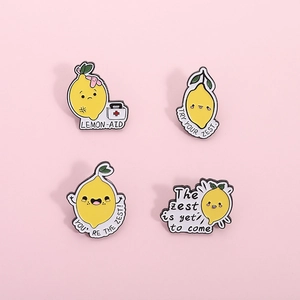 Lot de quatre broches en émail citron avec jeux de mots sur un fond rose uni