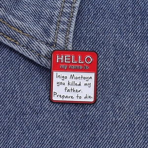 Detail of Hello My Name Is Inigo Montoya enamel pin on denim jacket fabric