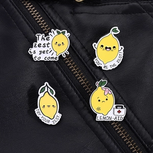 Detail von vier Cartoon-Zitronen-Emaille-Pins auf Lederjacke mit humorvollen Textgravuren