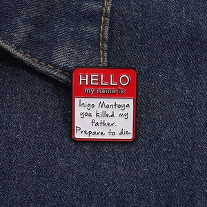 Detail of Hello My Name Is Inigo Montoya enamel pin on blue denim fabric texture