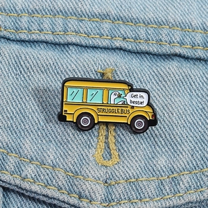Dettaglio di una spilla smaltata con bus di oca gialla su tessuto denim blu