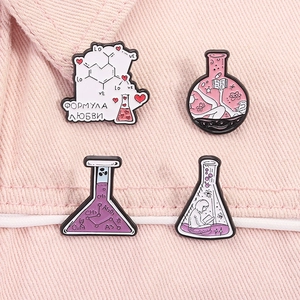 Macro shot of lab-themed enamel pins featuring a beaker and microscope on denim fabric