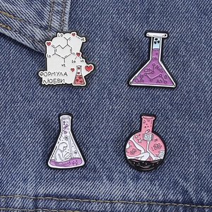Set of 4 chemistry enamel pins featuring lab beakers and formulas on blue denim