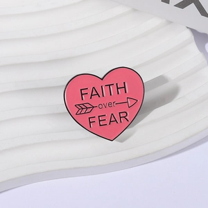 Detailed view of pink heart enamel brooch with Faith over Fear text and arrow detail