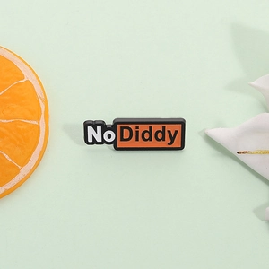 Broche créative No Diddy avec fond orange et bord noir sur un support de couleur verte