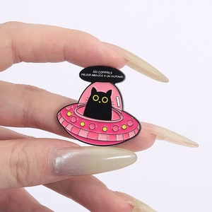 Gros plan sur le pin's en émail OVNI rose avec chat noir et texte espagnol sur fond blanc