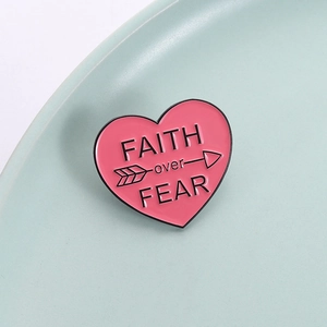 Pink heart enamel pin with Faith over Fear quote and black arrow details for accessories