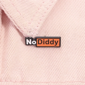 Détail du badge émaillé No Diddy fixé sur un tissu en denim rose comme accessoire