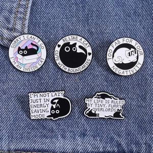 Close-up of five cute enamel cat pins on denim fabric with funny quote designs