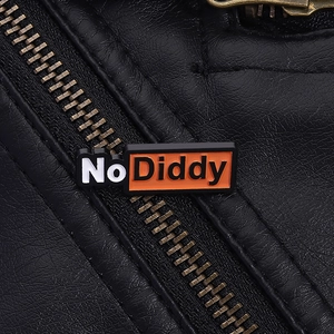 Gros plan d'un pin's émaillé No Diddy sur une veste en cuir noir avec détails en métal