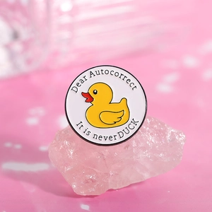 Détail du badge en émail avec le texte humoristique Dear Autocorrect It is never DUCK