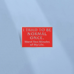 Detail showing red enamel pin with humor text I tried to be normal once on blue background