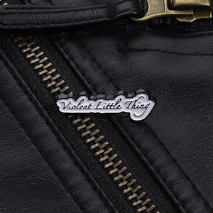 Détail du pin's en émail Violent Little Thing sur veste en cuir noir avec fermeture éclair