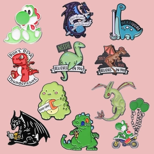 Flat lay of colorful enamel dinosaur pins featuring various cute cartoon designs