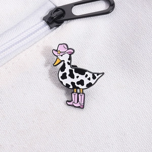 Cartoon enamel duck pin with pink cowboy hat and cow print pattern on white canvas bag