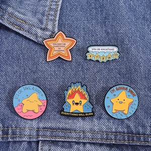 Set of five vibrant enamel star pins with motivational quotes on blue denim fabric