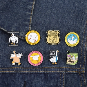 Close-up of eight cute enamel silly goose pins displayed on a blue denim jacket collar