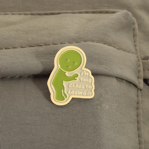 Detail of green Smiski pin with text I'M THIS CLOSE TO LOSING IT on canvas bag