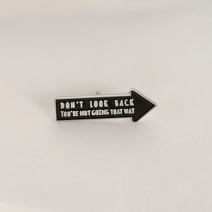 Macro view of black enamel arrow brooch with motivational engraving and silver metal edges