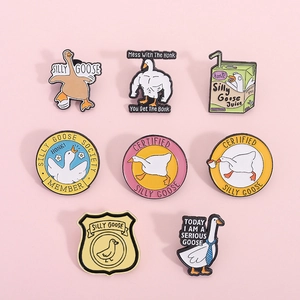 Flat lay of eight colorful silly goose enamel pins on a soft pink background